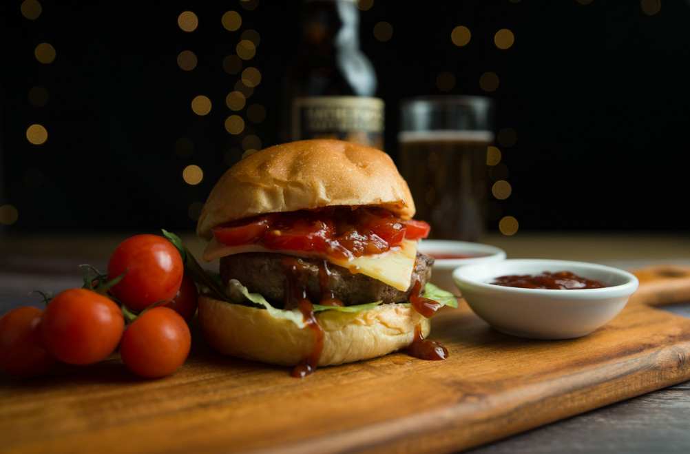 Food photography: Cheeseburger with relish, sauces and vine tomatoes